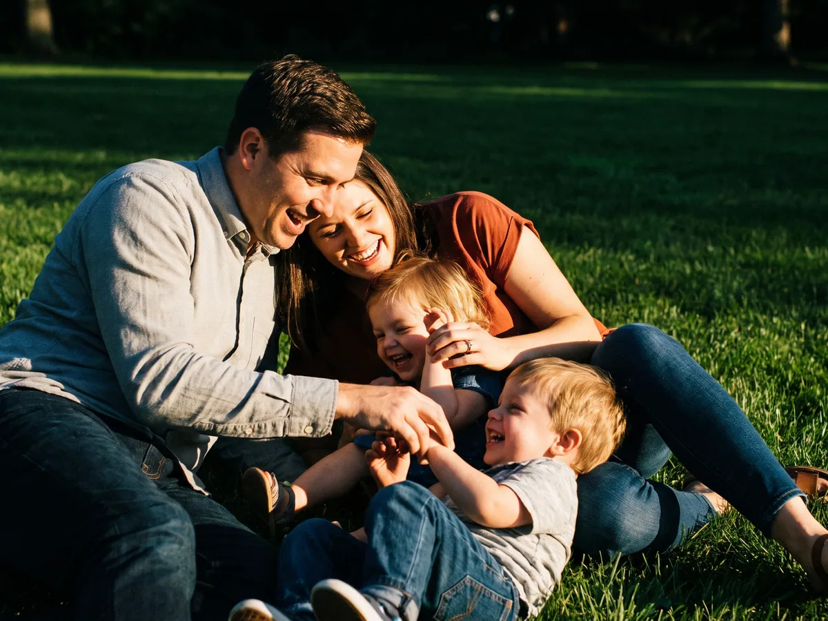 Una familia de cuatro riendo juntos en el césped