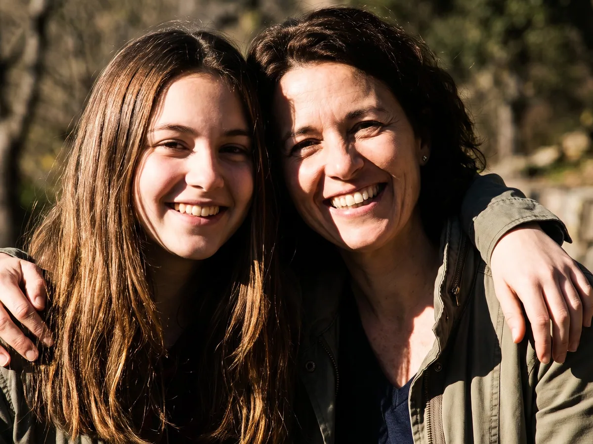 A teenage girl and her mom smiling outdoors